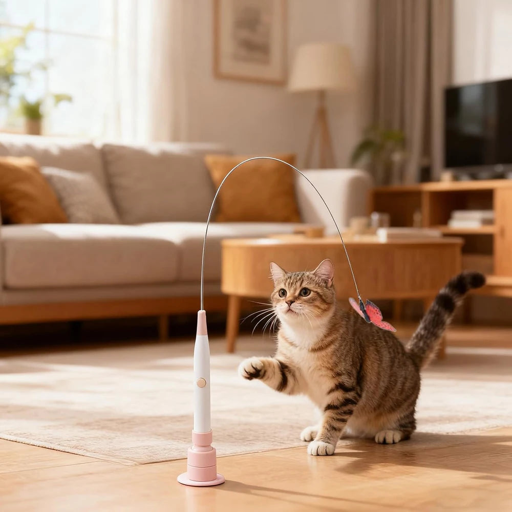 A tabby cat playing with an electric rotating butterfly toy that has a suction cup base on a wooden floor.