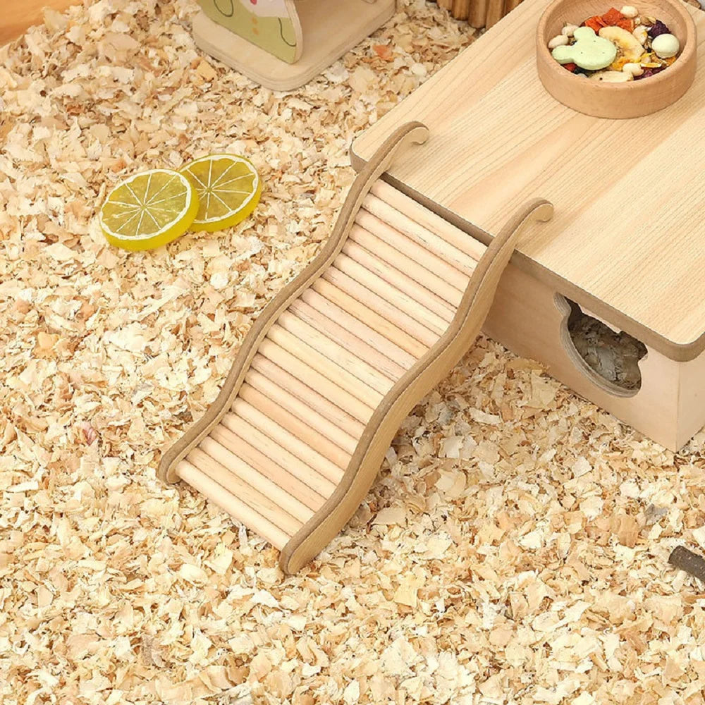 A wooden wave staircase hamster toy with a curved slide is placed on a light wooden tray on a wood-shavings surface.