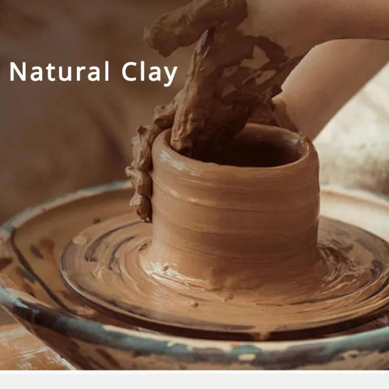 A hand is shaping a piece of natural clay into a cylindrical form, resting on a round wooden base.