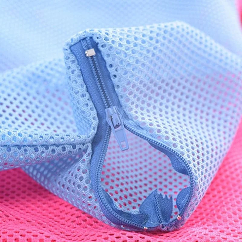 Light blue mesh grooming bag for cats shown folded on a pink surface