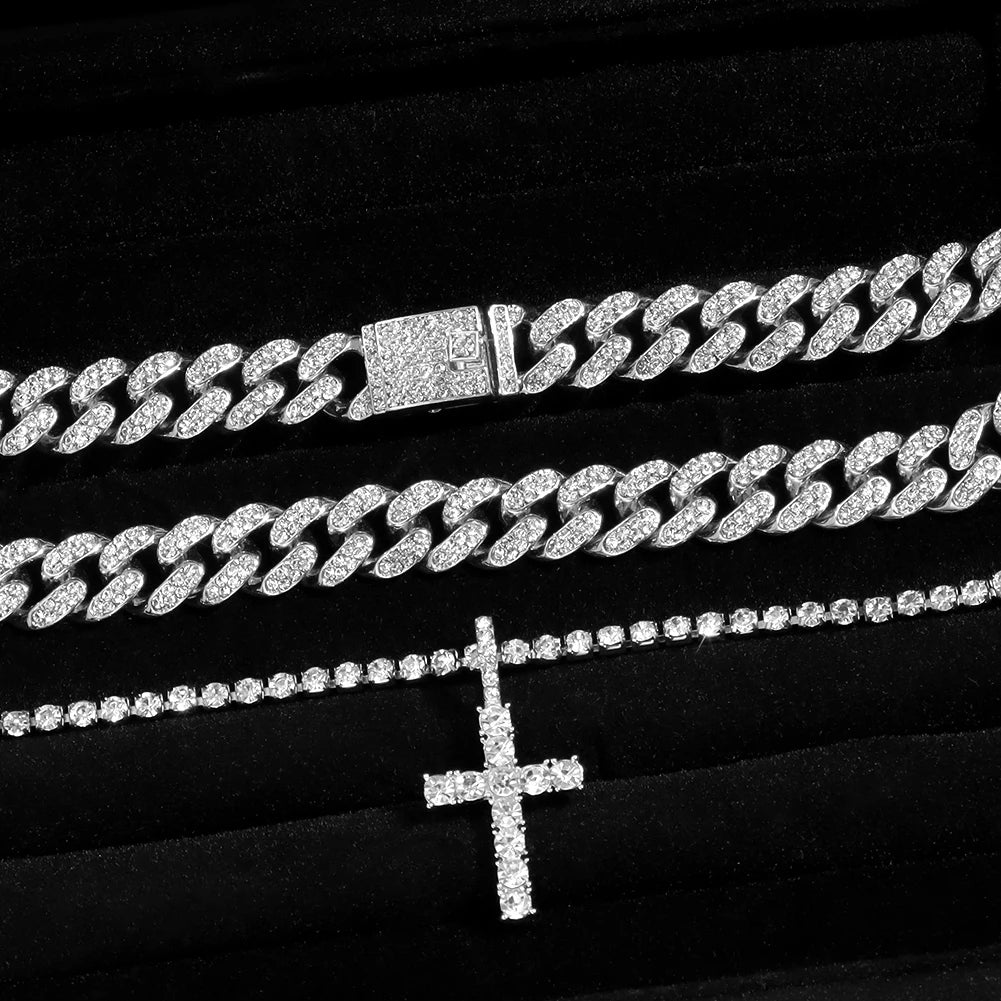 A set of dainty diamond Cuban link necklaces and a cross pendant displayed on black velvet.
