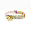 A colorful lace flower cat collar with a bell and an orange gemstone pendant.