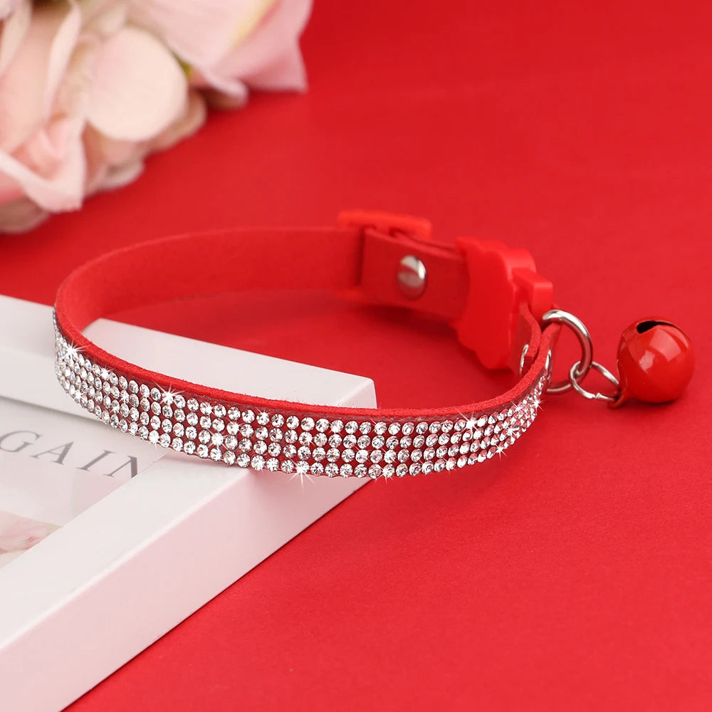 Red suede collar adorned with clear rhinestones and a safety breakaway buckle resting on a red background.