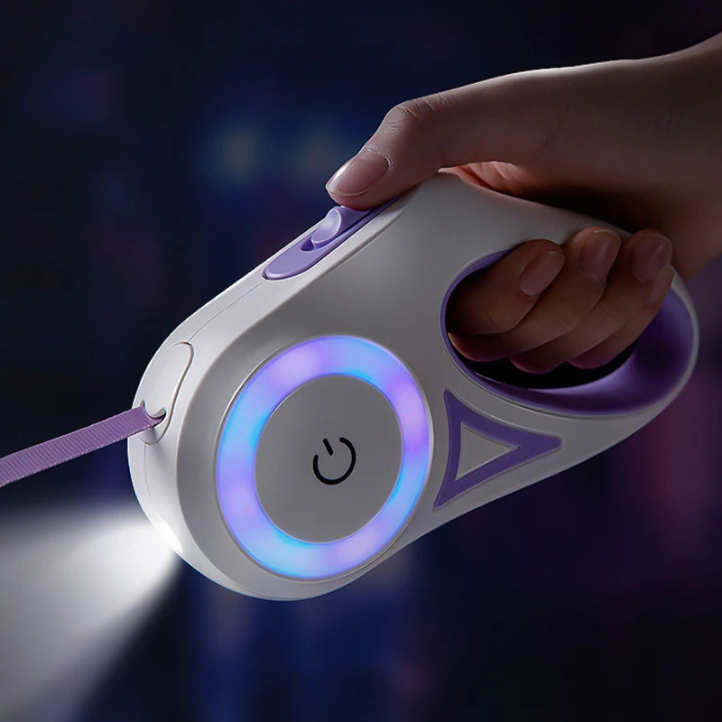 A hand holds a white LED retractable dog leash with a purple grip and a glowing blue light.