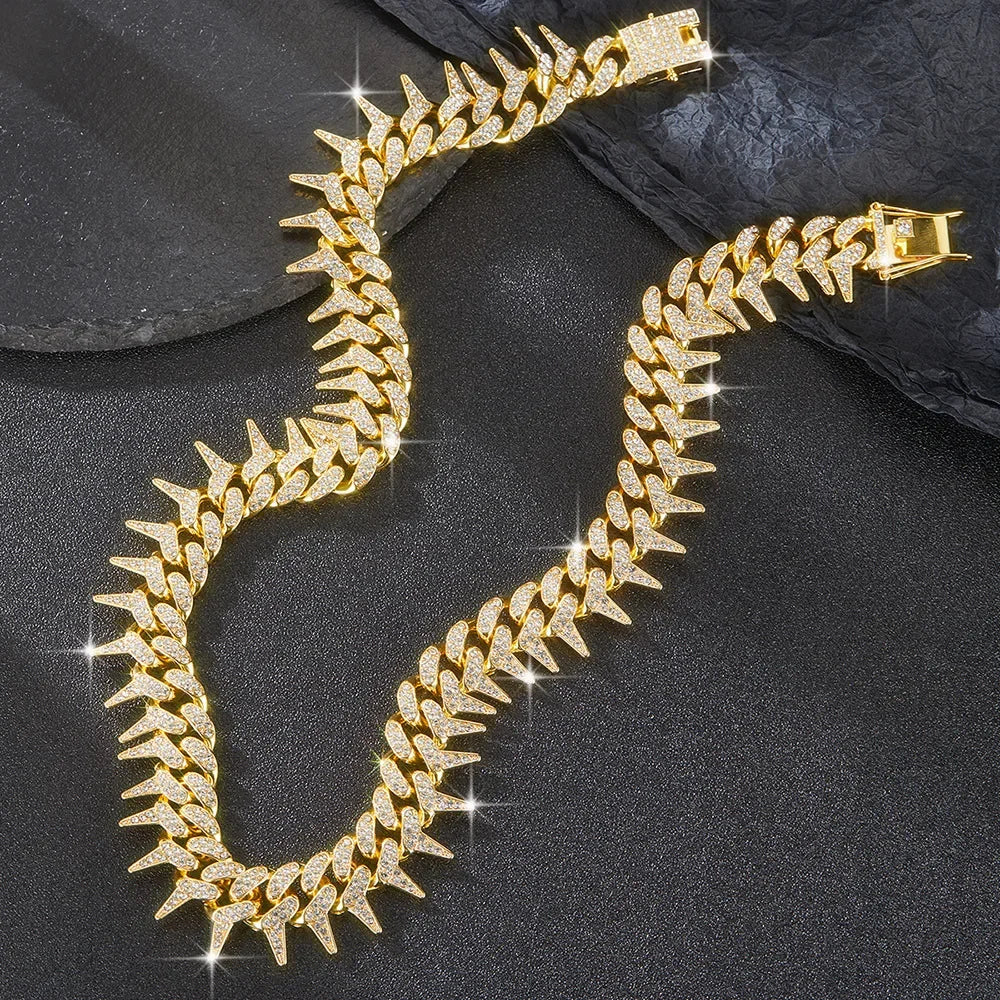 A gold spiked Cuban chain bracelet with diamond accents displayed against a dark background.