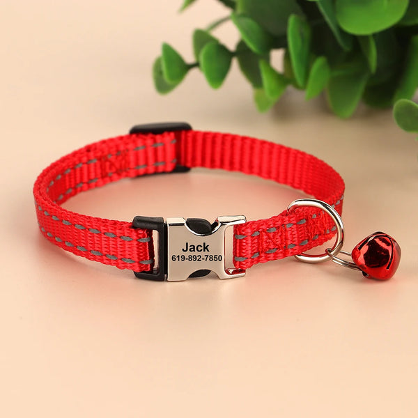 Red reflective nylon cat collar with a black buckle, ID tag, and a small red bell attached.