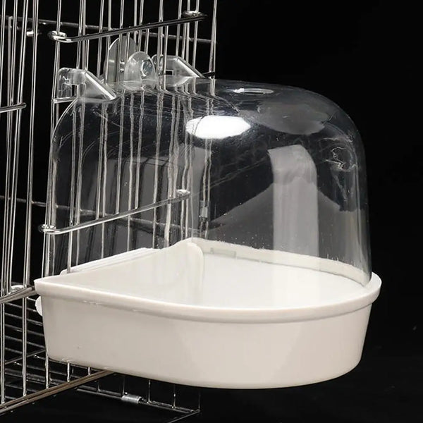 Une vasque à oiseaux claire suspendue pour perruches est visible dans une cage de fils.