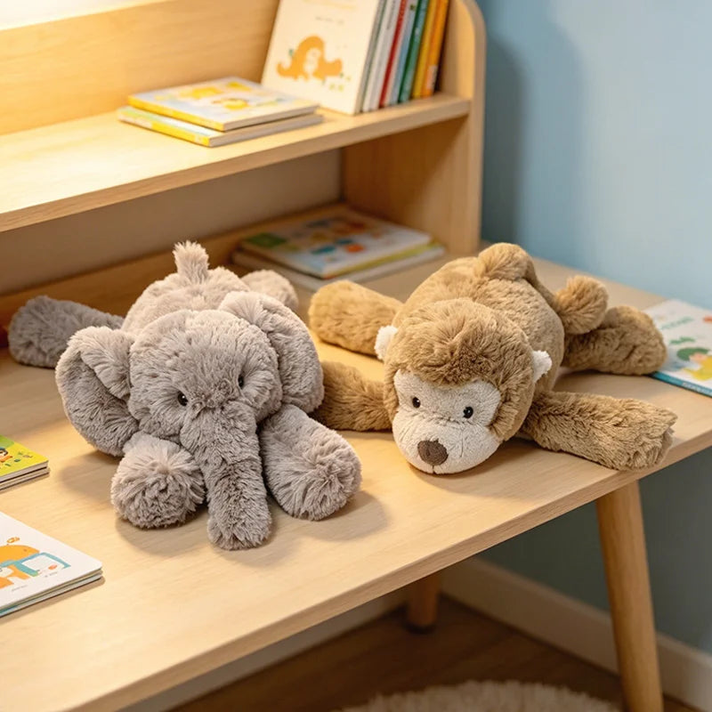 A soft gray elephant monkey plush toy lying on a wooden shelf next to books.