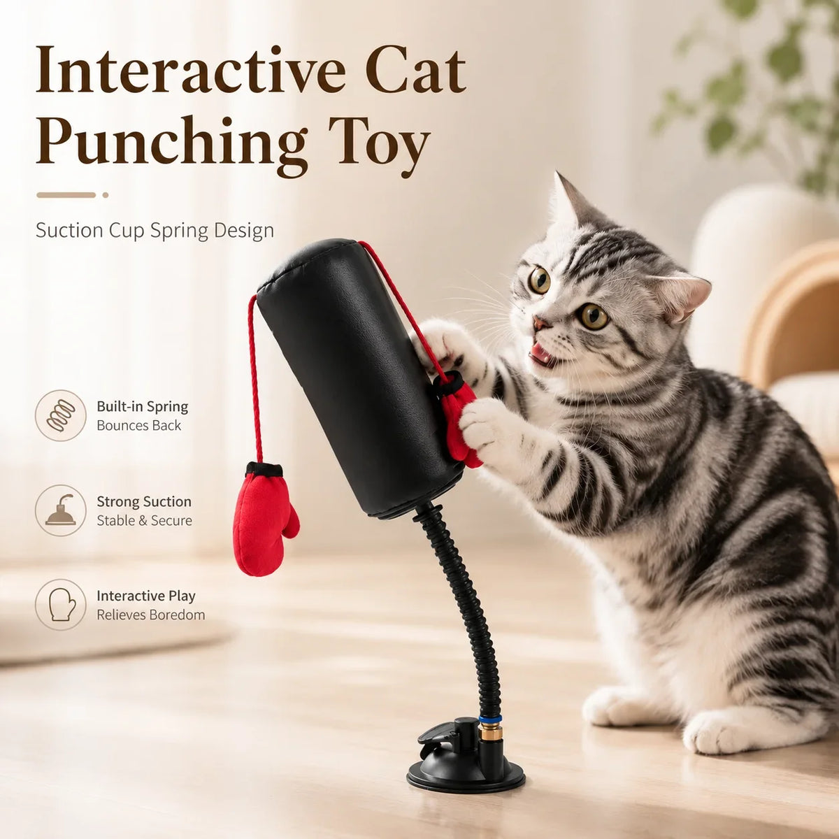 A tabby cat is playing with an interactive cat punching toy featuring a suction cup design and red boxing gloves.