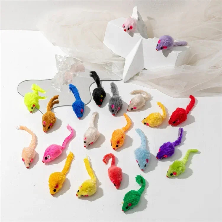 Collection de jouets à la souris et clochettes de chaton colorés et duveteux sur une surface blanche.