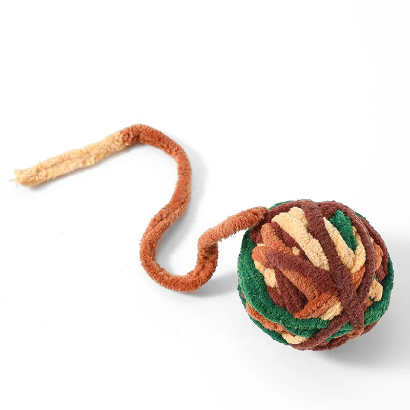 A soft plush cat toy ball with a bell, featuring brown and green textured fur.