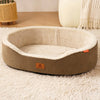 A beige dog house bed with a rounded shape and a brown exterior sits on a fluffy white rug.