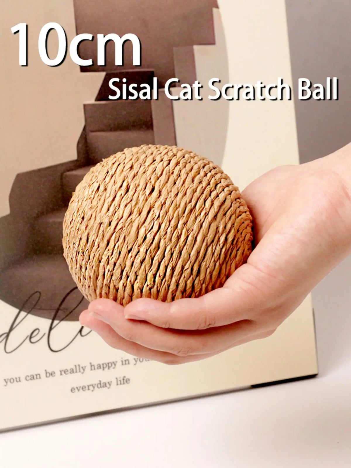 A hand holds a round, textured sisal cat scratch ball.
