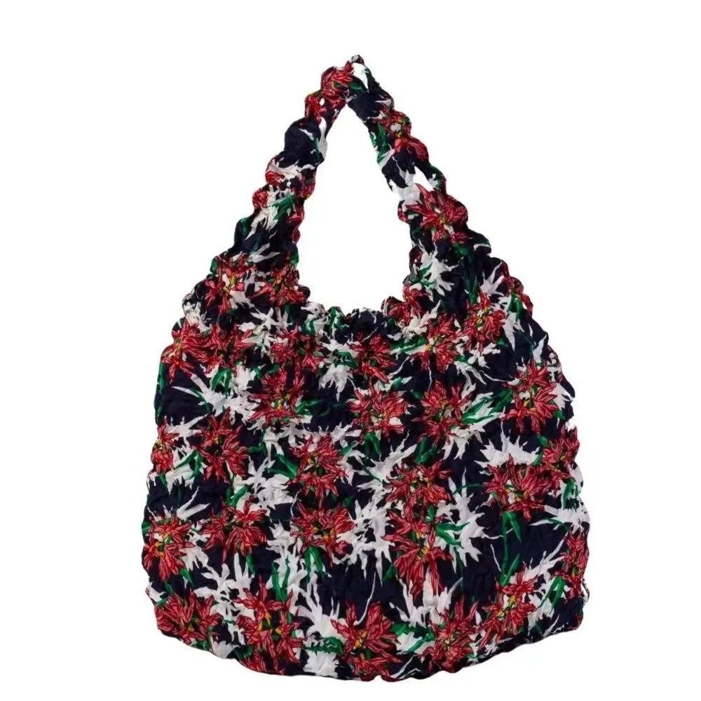 A floral patterned fabric shopping tote bag with a dark background and white, red, and green leaves.