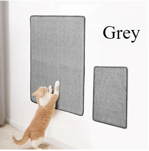 A tabby cat is climbing on a grey wall-mounted sisal scratching mat.