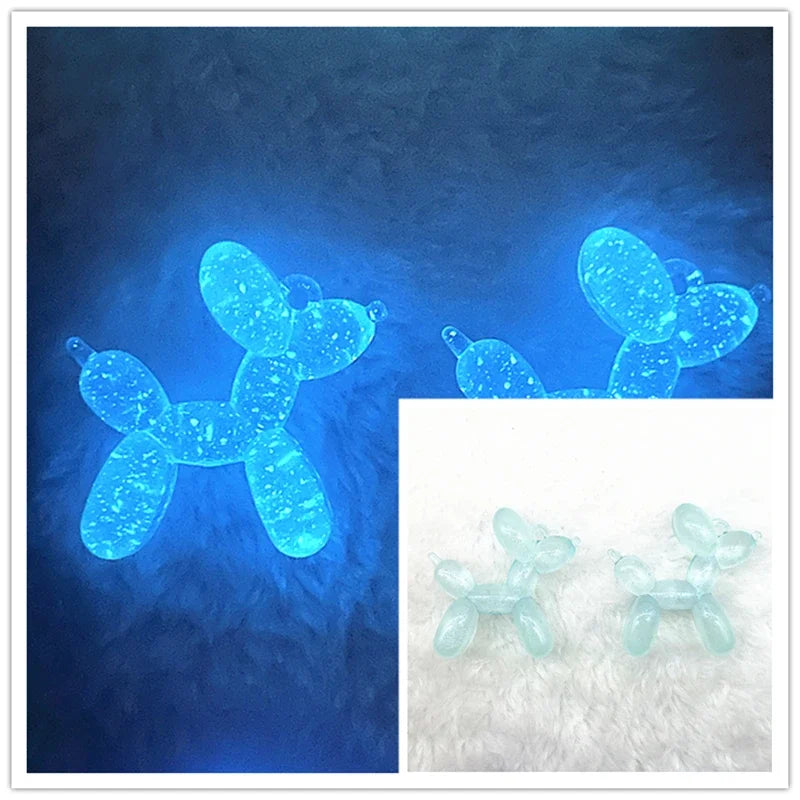 Two glowing blue acrylic balloon dog charms against a dark blue background.