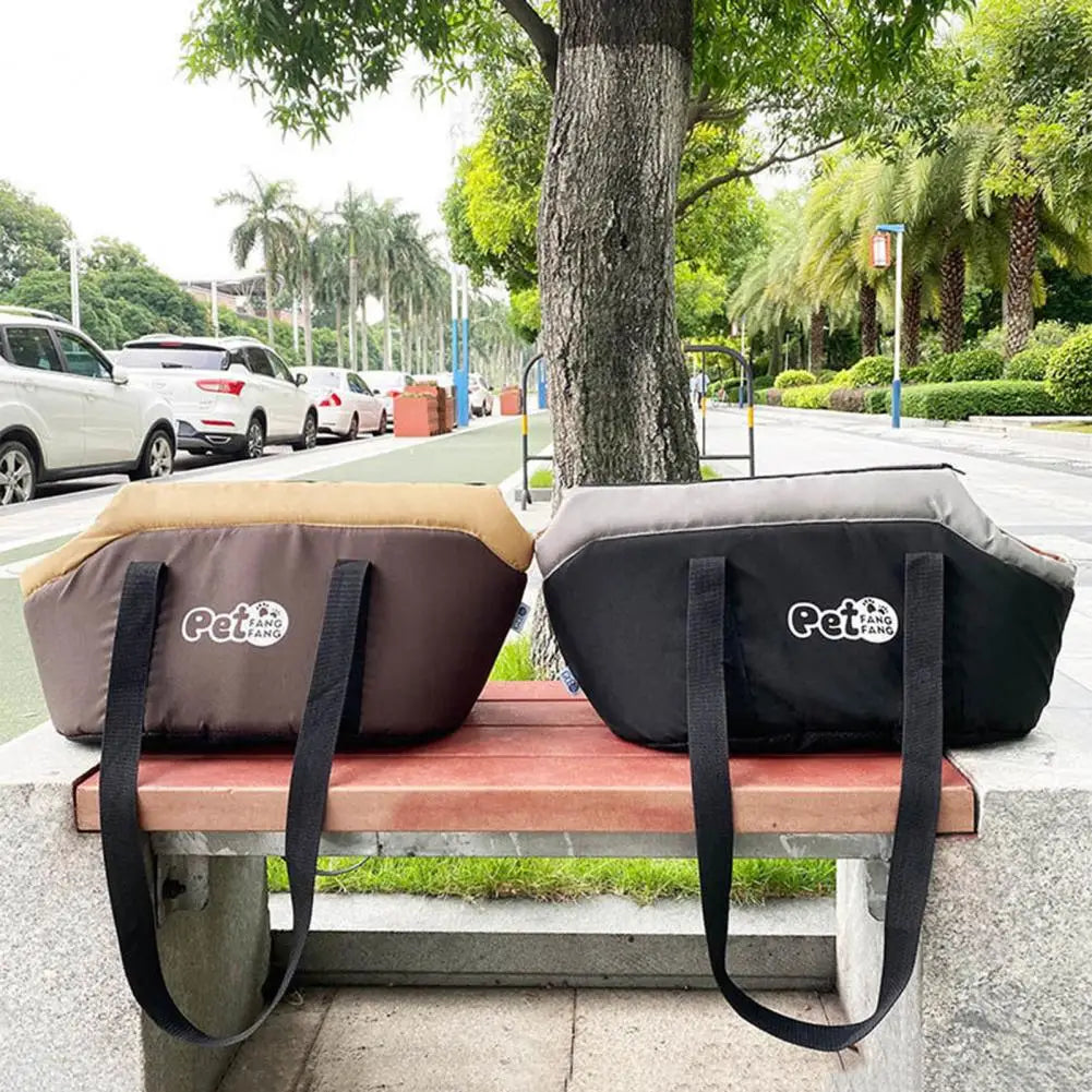Cage de transport pour animal gris foncé à parois souples avec un coussin intérieur beige, posé sur un banc de parc en bois.