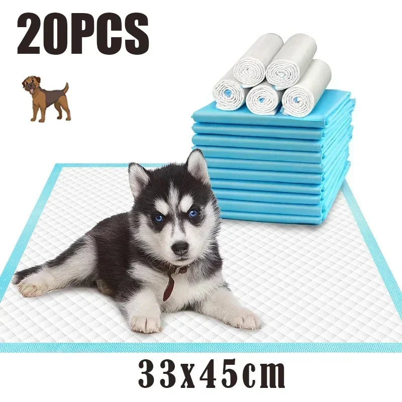 A fluffy husky puppy lies on a white training pad next to a stack of blue absorbent pads.
