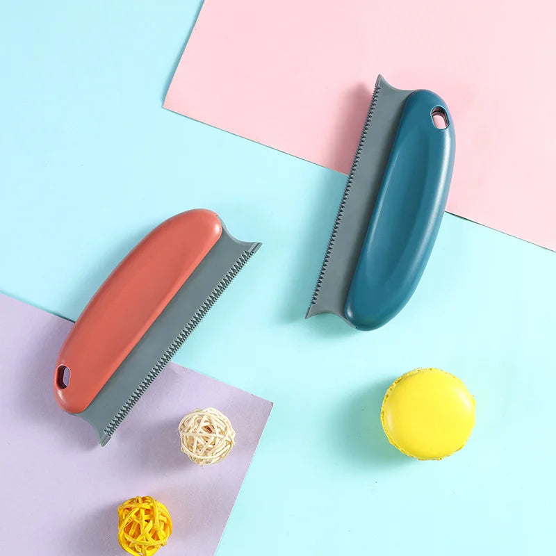 A portable fabric and pet hair remover brush in orange and teal colors resting on a light blue background.