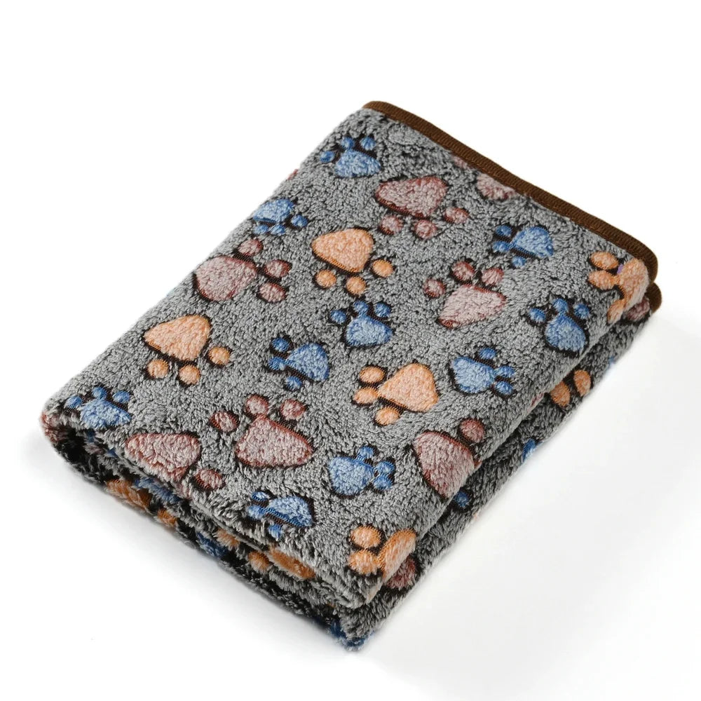 A cozy thick fleece pet blanket featuring a gray background with paw print patterns in brown and blue.