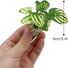 A hand holds a realistic plastic plant with green and white patterned leaves and a secure base.