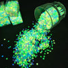 A clear jar filled with bright green glow-in-the-dark resin pebbles and spilled onto a dark surface.