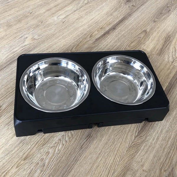 Black elevated dog feeder with two stainless steel bowls on a wooden surface.