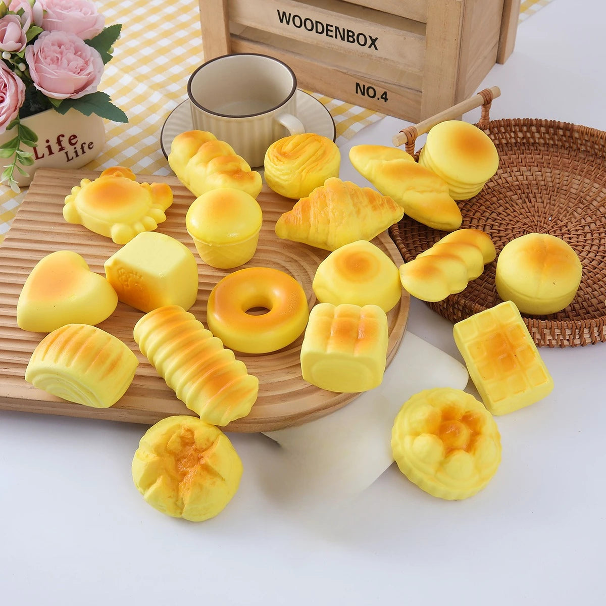 A variety of yellow baked goods, including rolls and buns, are arranged on a wooden board next to a woven basket.