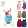 A white dog wearing a bright blue knitted sweater, shown next to various colored knitted dog sweaters.