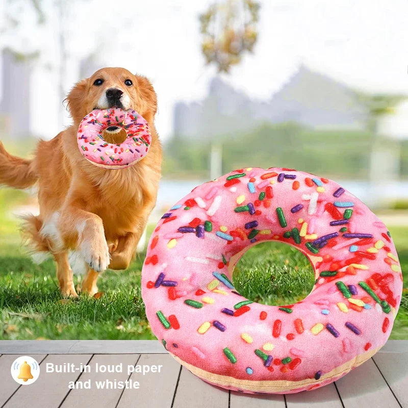 Un golden retriever interagit avec un jouet en peluche rose en forme de donut qui fait du bruit.