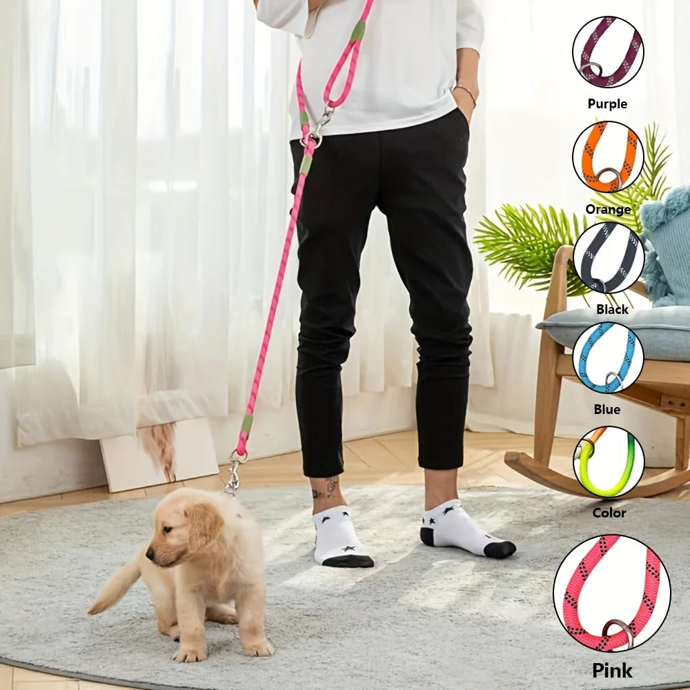 A person is holding a pink dog leash with various colored reflective stripes, including purple, orange, black, blue, and pink