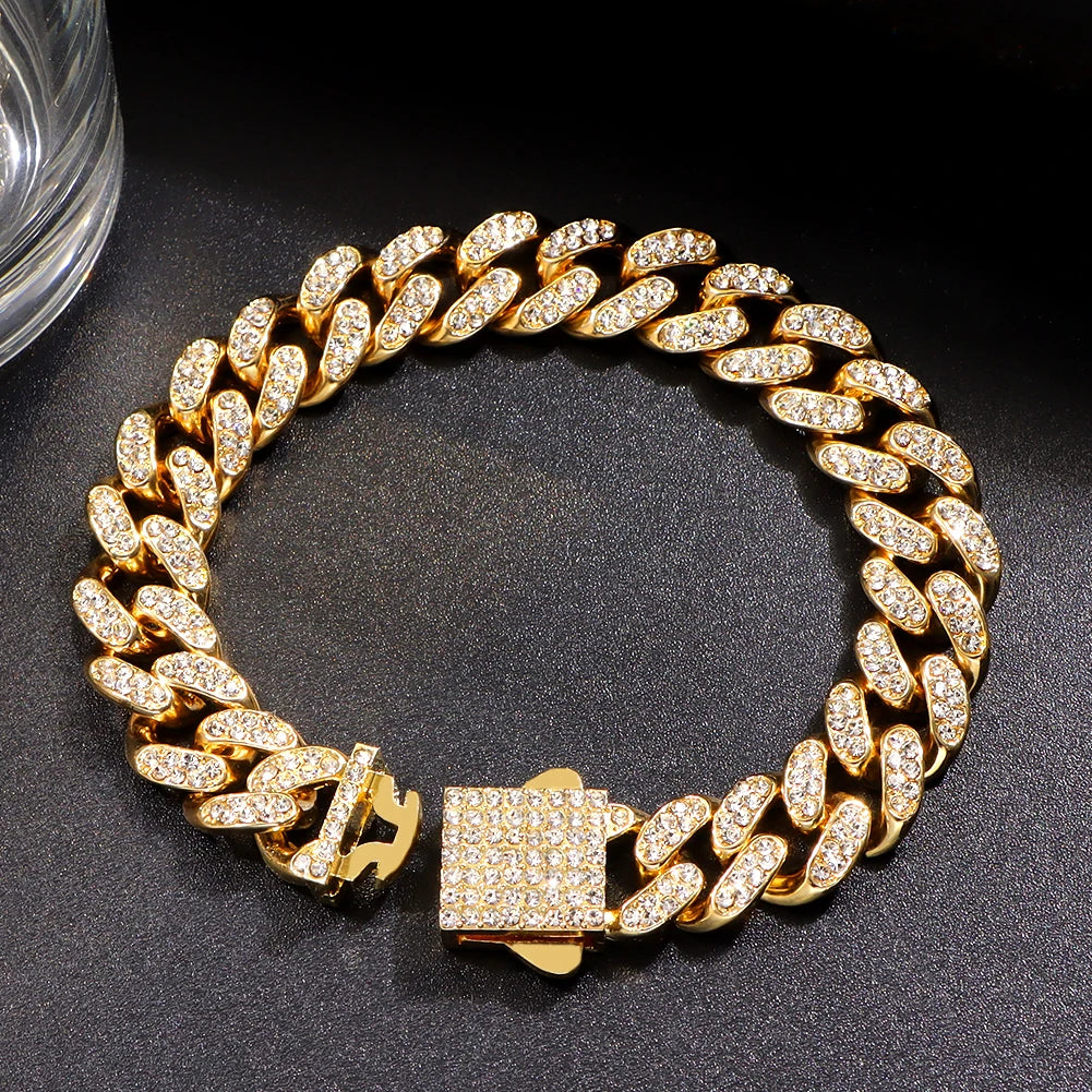 A gold iced out Cuban link bracelet with rhinestone accents displayed on a dark surface.