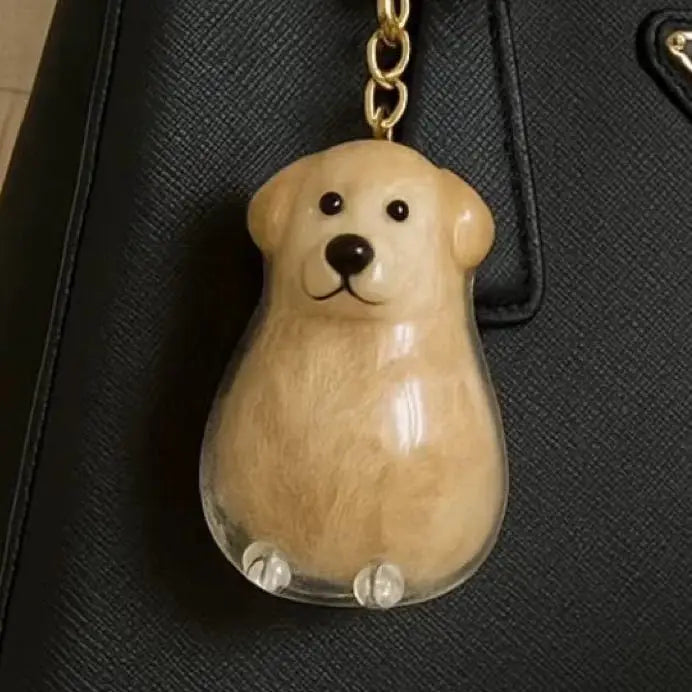 Un charm en verre clair en forme de tête de chien brun clair avec des traits noirs, suspendu à une clé USB dorée.