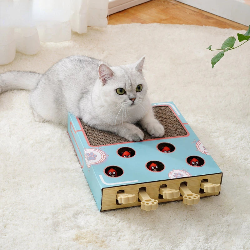 A gray cat is resting on an interactive whack-a-mole scratching board with small wooden pegs on a white fluffy rug.