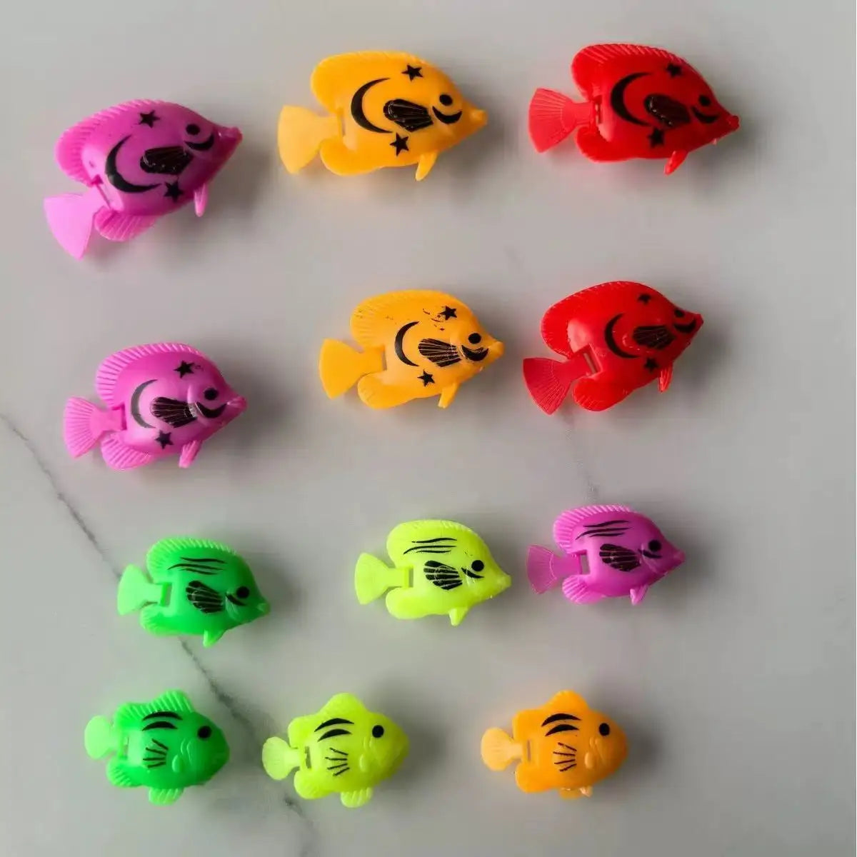 A collection of ten soft rubber goldfish bath toys in various colors including pink, yellow, and red.