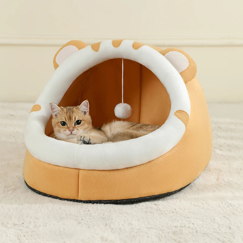 Un pequeño gato naranja está relajándose dentro de una cama de felpa redonda beige y blanca.