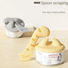 A yellow pet feeding spoon with a cat design is shown next to a silver can opener and a sealed food container.