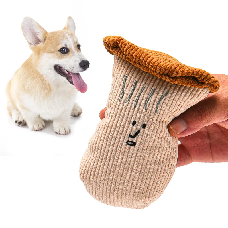 Une main tient un jouet en peluche tricoté en forme de visage avec moustaches et une oreille, à côté d'un petit chien brun cl
