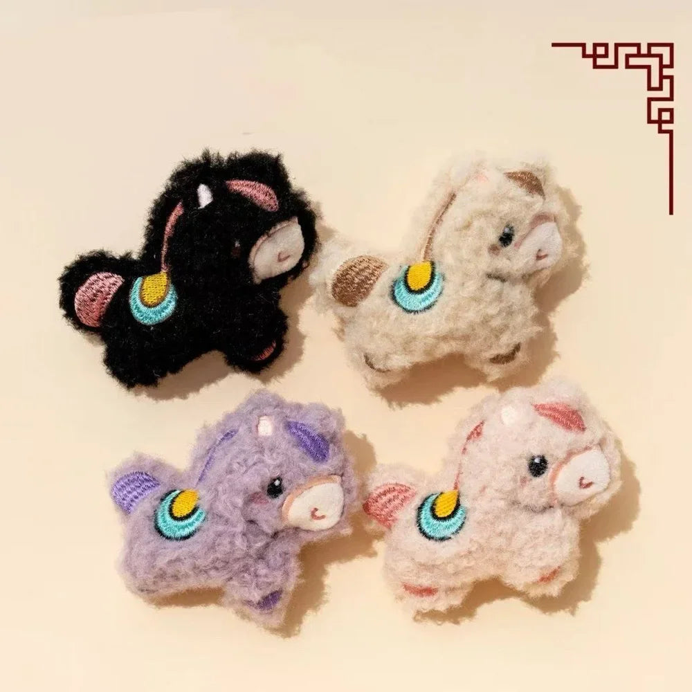 Three small plush dog toys in black, white, and purple with colorful accents