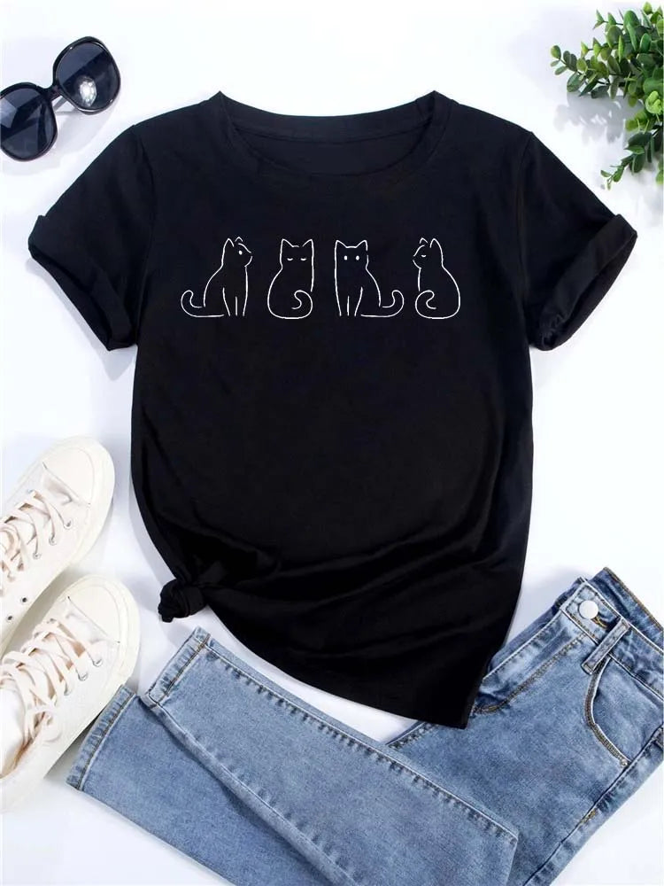 Camiseta negra de manga corta con un dibujo lineal blanco de tres gatos, junto a jeans y gafas de sol.