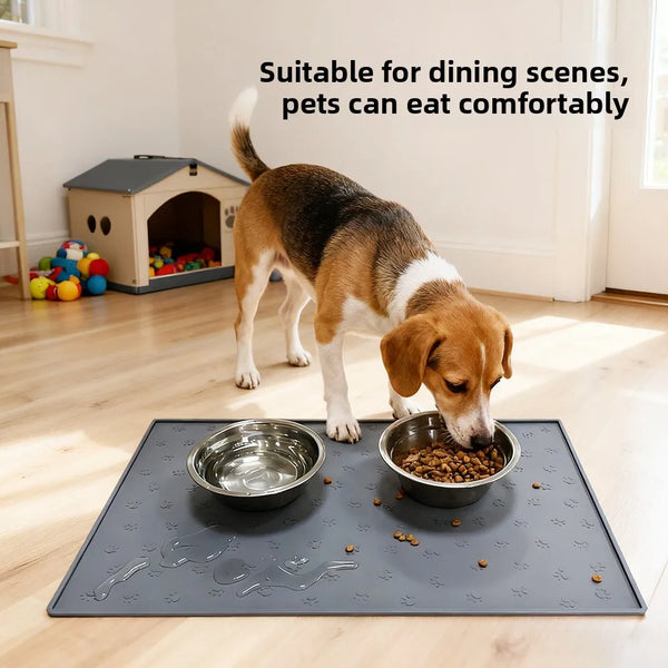 A brown dog is eating from a metal bowl on a dark silicone pet feeding mat indoors.
