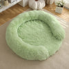 A round, light green faux fur dog bed resting on a beige rug.