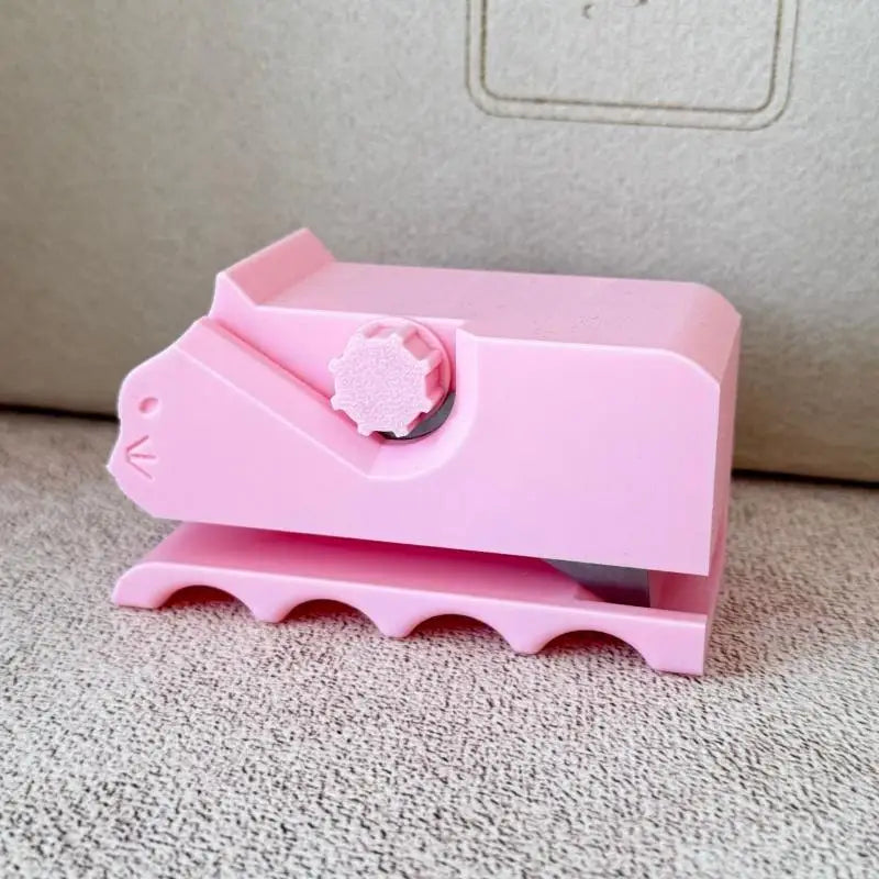 A pink handheld cardboard strip cutter tool with a pink plastic body and a pink cutting blade.