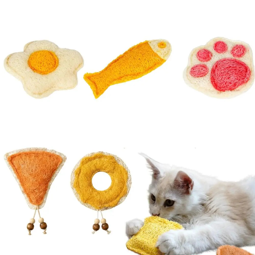 A collection of natural loofah cat chew toys including a fried egg shape, a yellow fish shape, and a pink paw print toy.