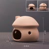 A light beige ceramic aquarium shrimp hideaway cave with an entrance hole and a small circular hole.