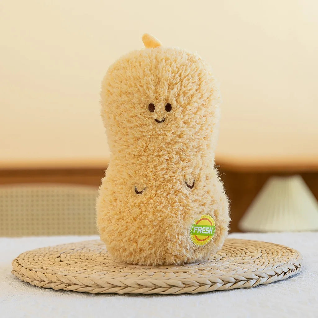 A fluffy, light brown plush vegetable doll resembling a peanut sits on a woven mat.