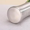 A silver, cylindrical portable dog water bottle with a built-in bowl resting on a white surface.