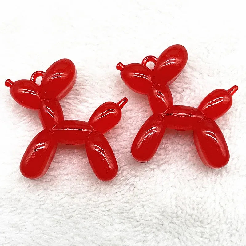 A pair of bright red acrylic balloon dog charm pendants for jewelry making and keychains.
