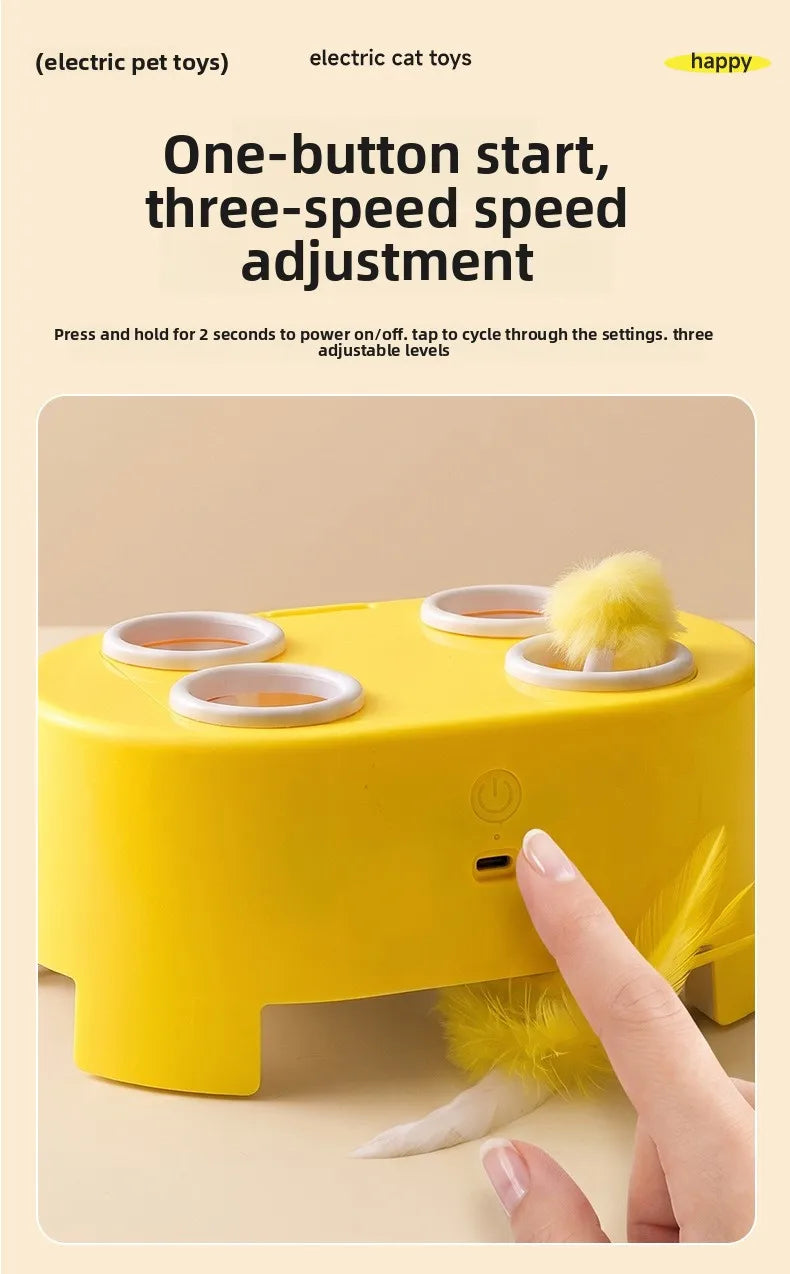 A yellow electric cat toy is shown with a hand interacting with the device and a feather ball.