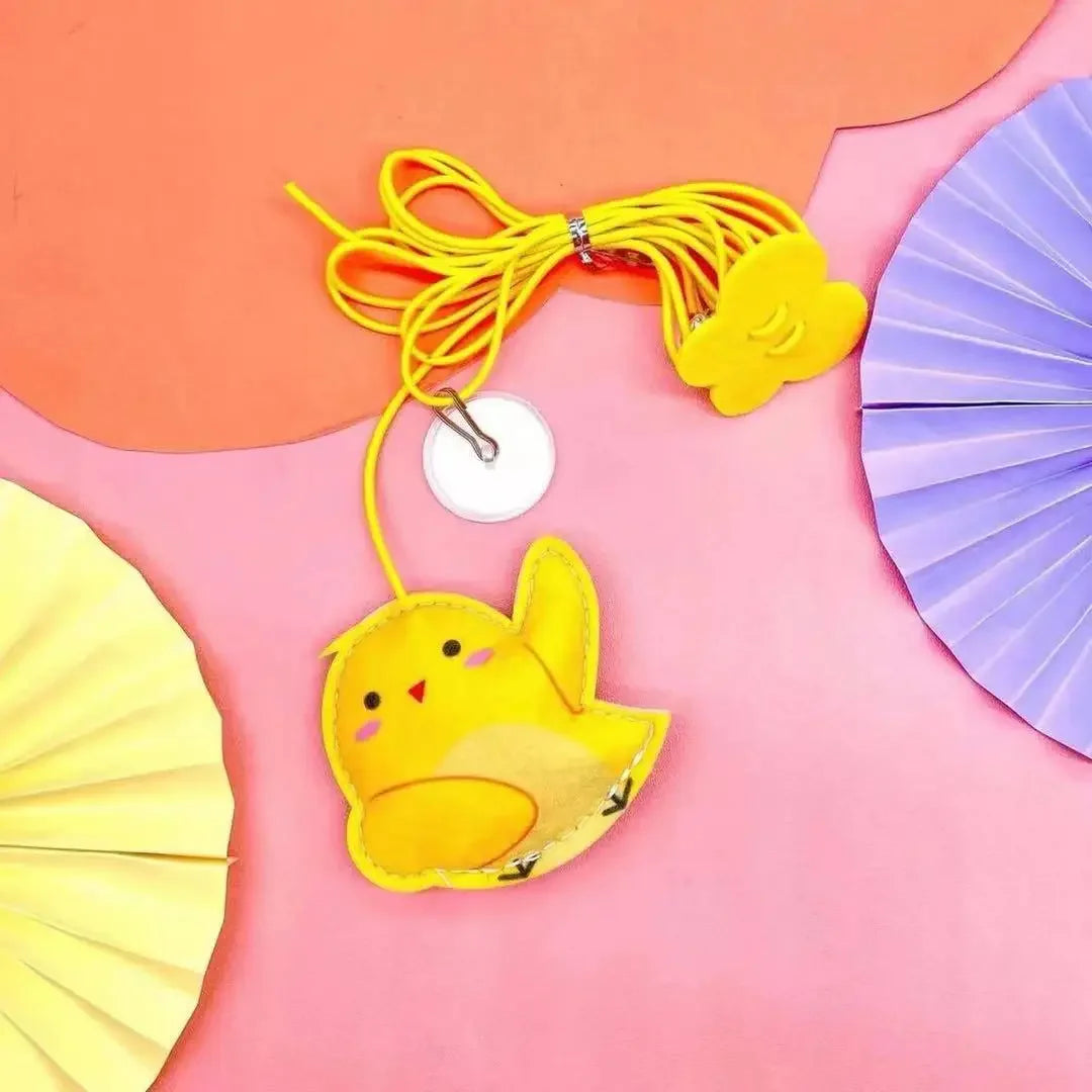 A yellow felt cat toy is hanging from a bright yellow rope against a pink background.